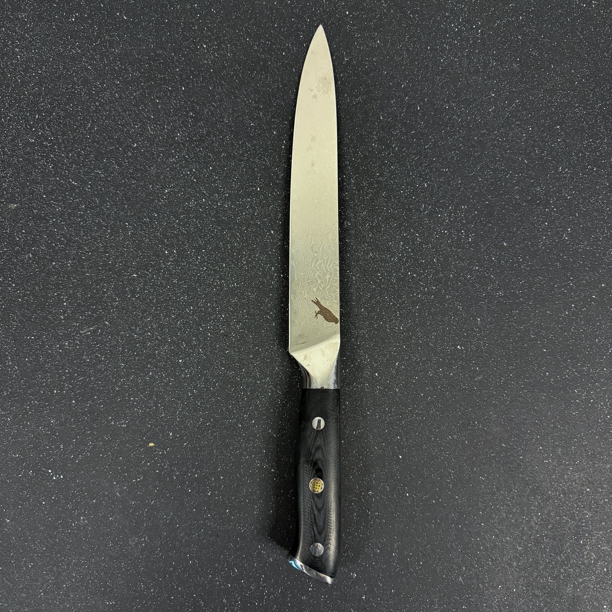 Cuchillo Carving Rauka Cay con hoja de acero Damasco y mango G10, ideal para cortes largos y precisos en cocina